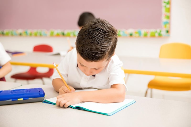 young boy writing in notebook