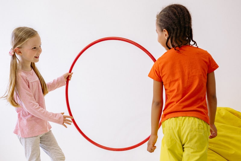 two kids playing with a hula hoop