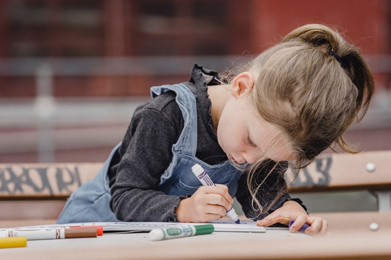 young girl coloring with markers