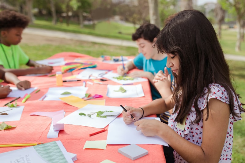 kids doing crafts on a table outside