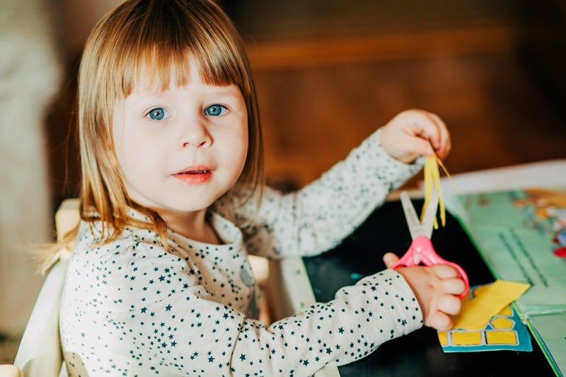 young girl cutting with scissors