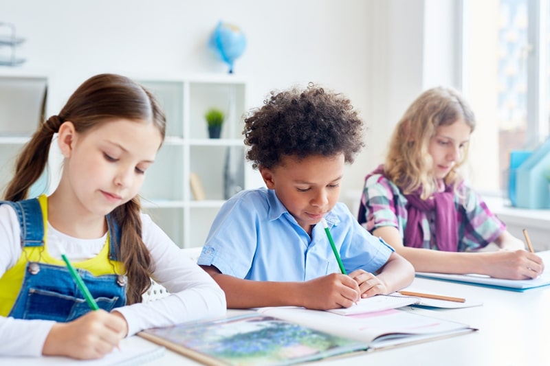 three kids studying in a classroom