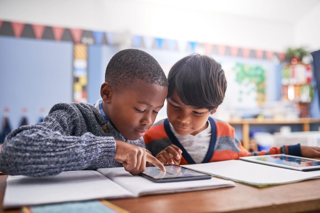 two boys playing on tablet in classroom