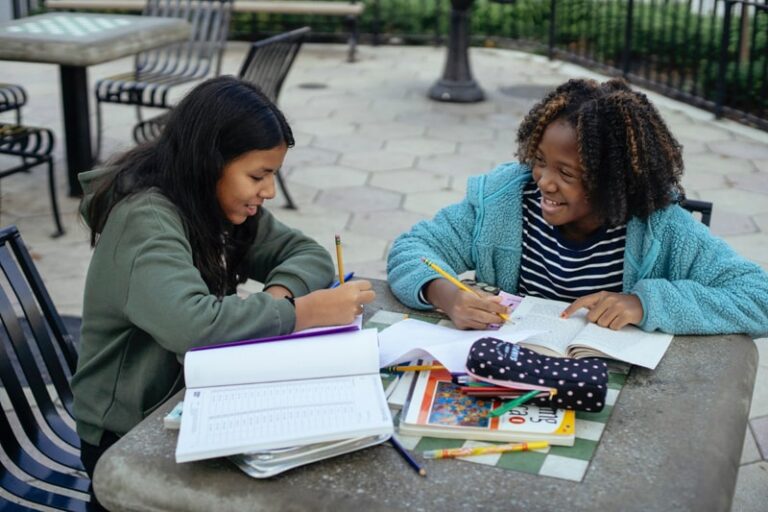 two girls studying outside at a table