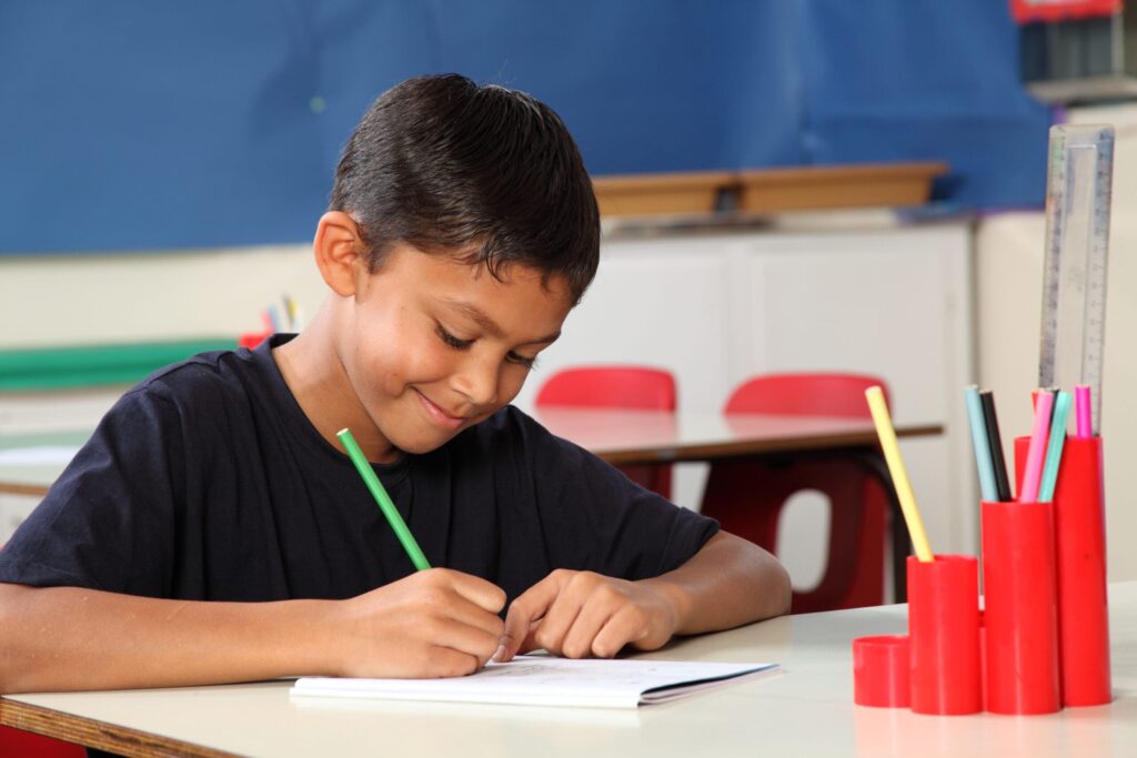 young boy writing in a classroom